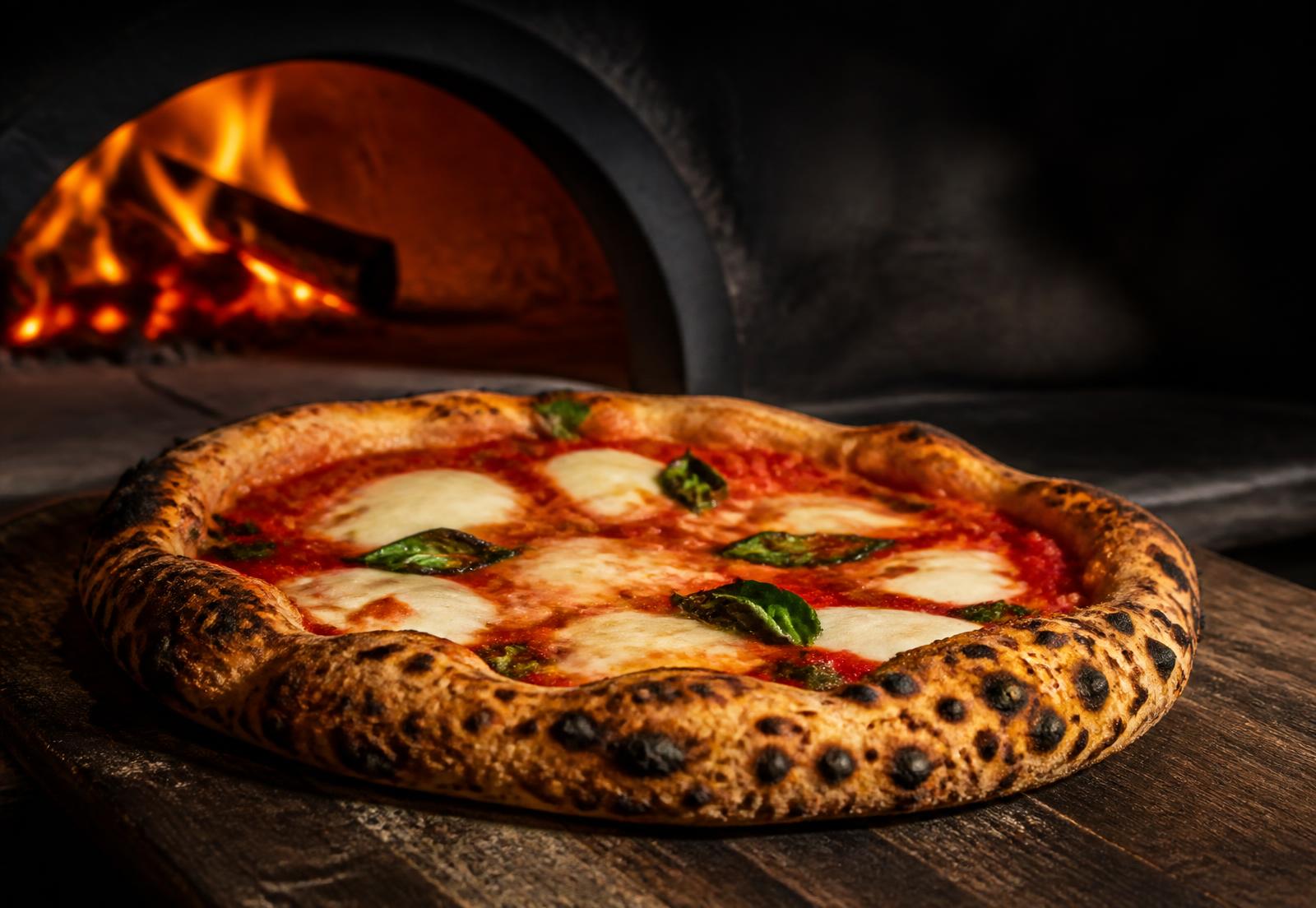 Authentische italienische Pizza vor dem lodernden Holzofen